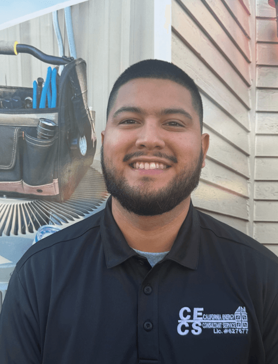 Smiling male employee wearing dark CECS polo shirt standing in front of truck with tools and equipment