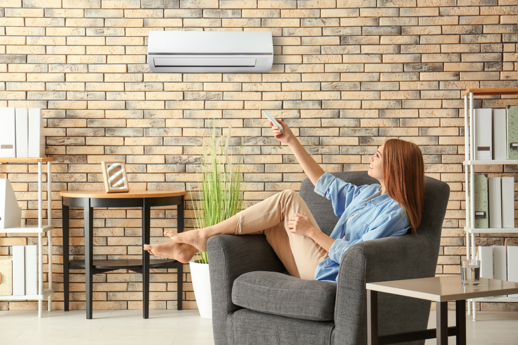 Barefoot woman turning on an air conditioner